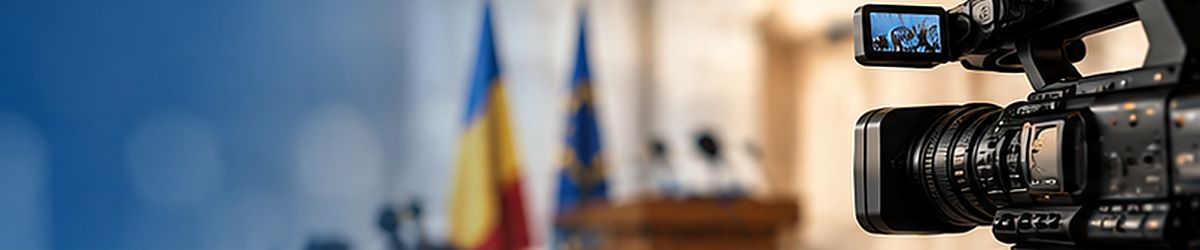 Cameră de filmat într-o sală de şedinţe, cu drapelele României şi ale Uniunii Europene